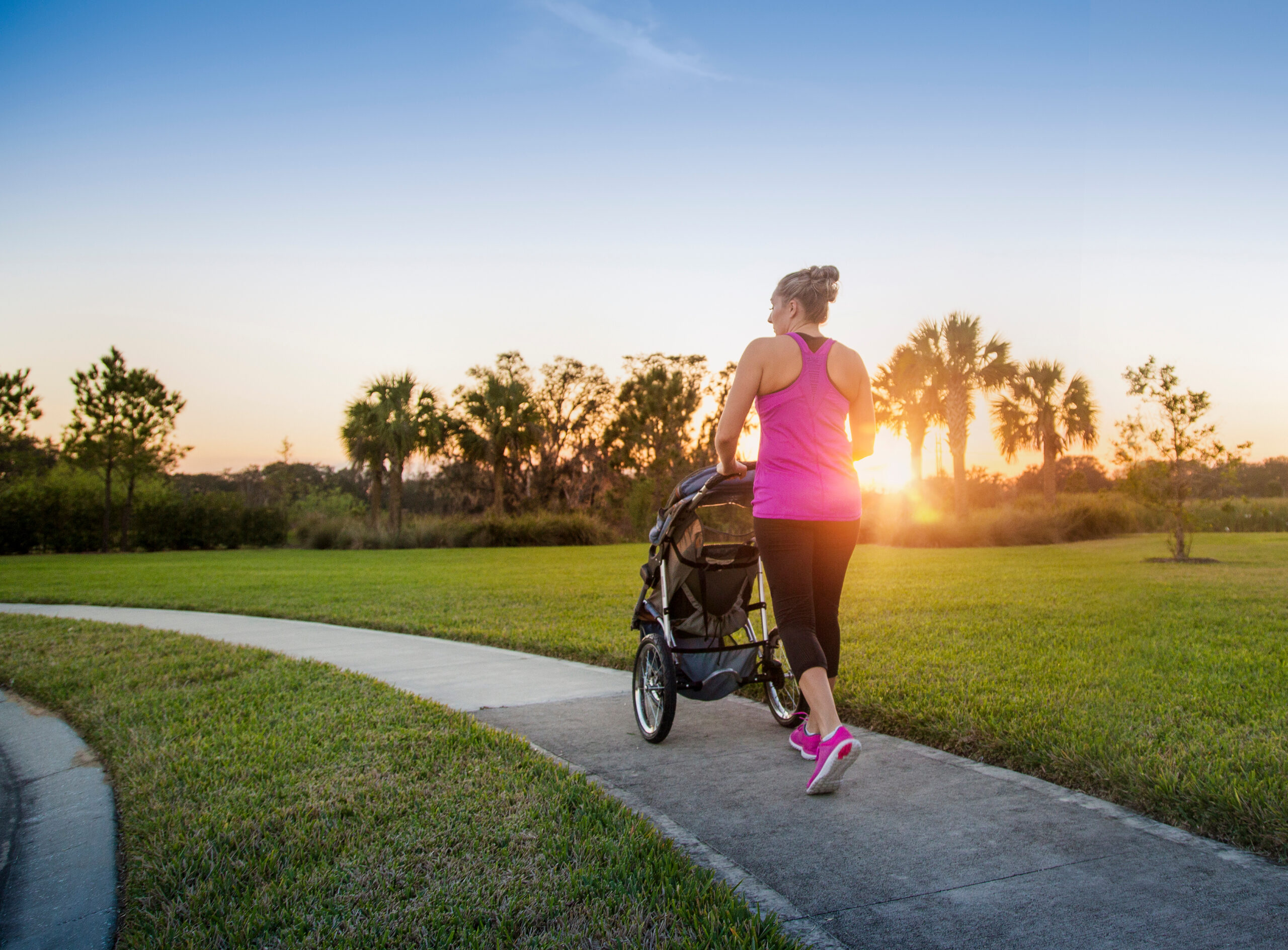 woman learning how to start running postpartum with stroller outside at sunset